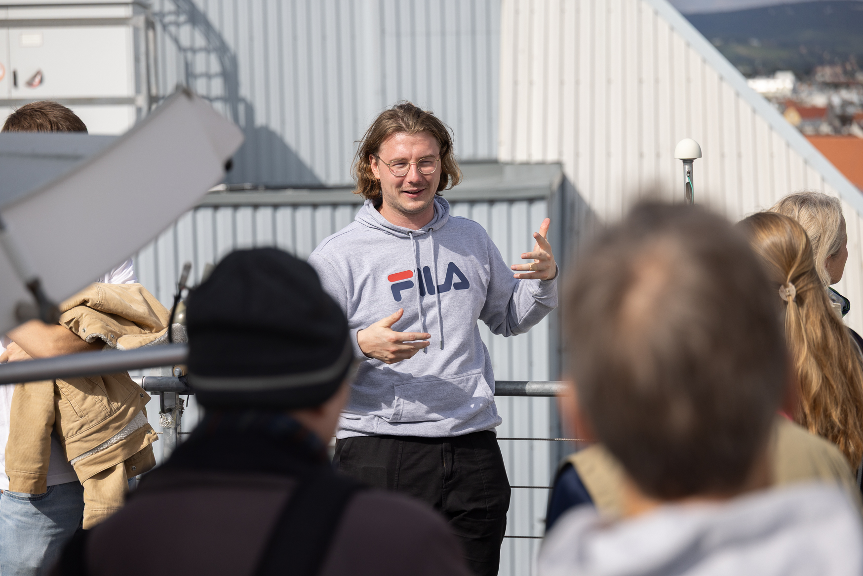 A scientist on the roof of the building, explaining the Hedy Lamarr Telescope