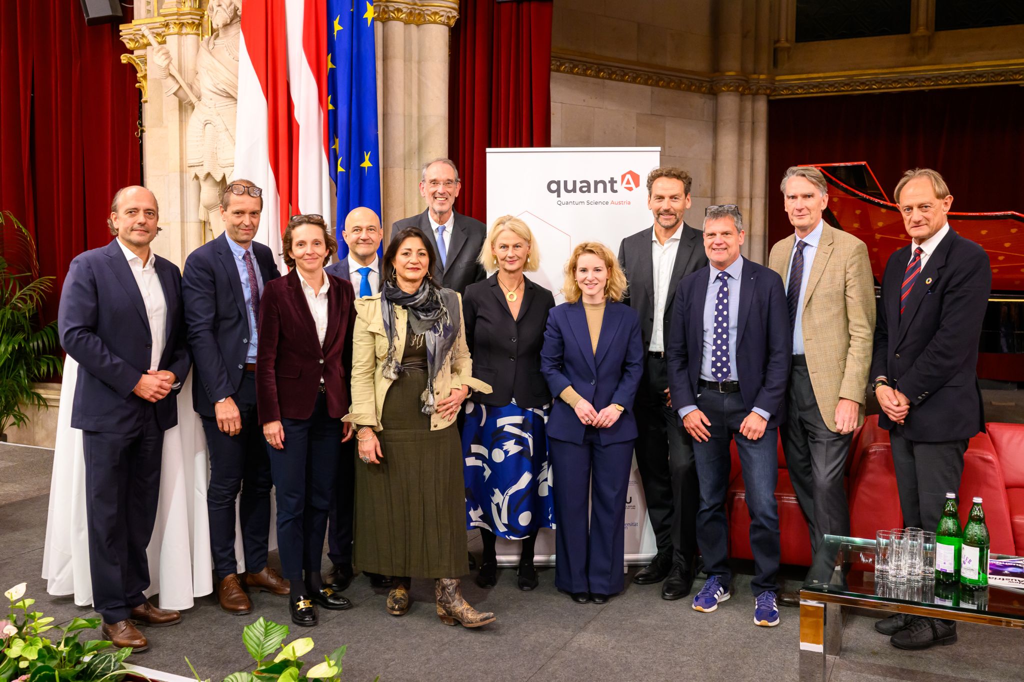 Invited guests from science and research pose for a group photo in front of the QuantA roll-up
